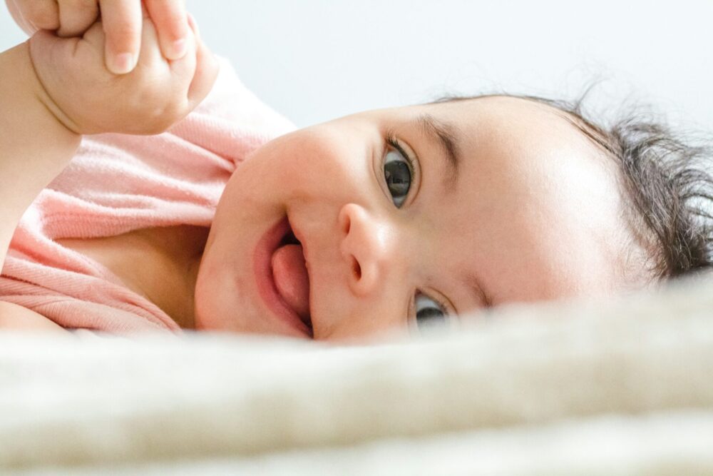 a baby smiling lying on a blanket