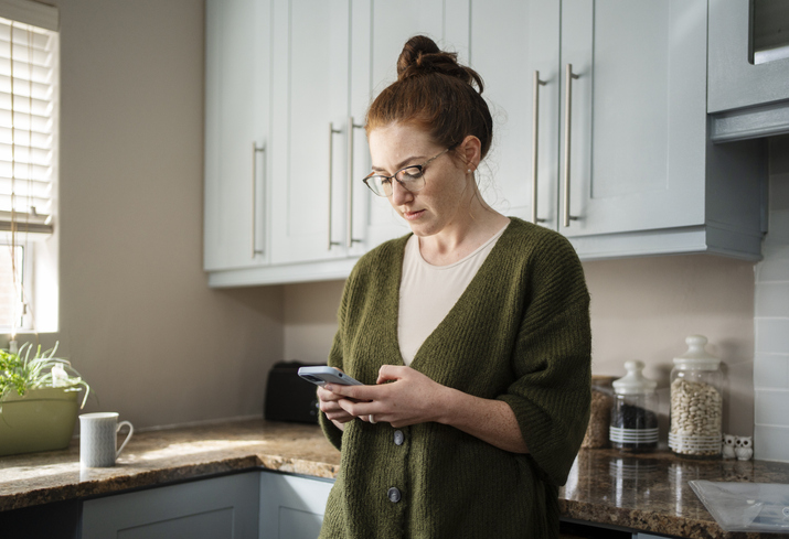 Young woman on her phone researching IVF pricing to understand the costs