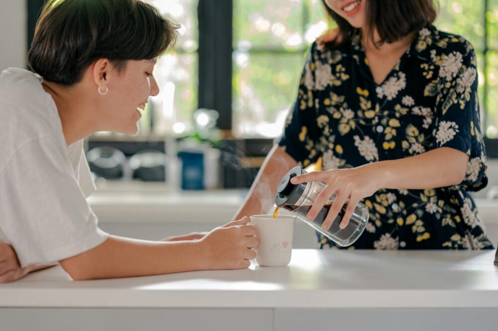 Two people talking over a drink in a kitchen
